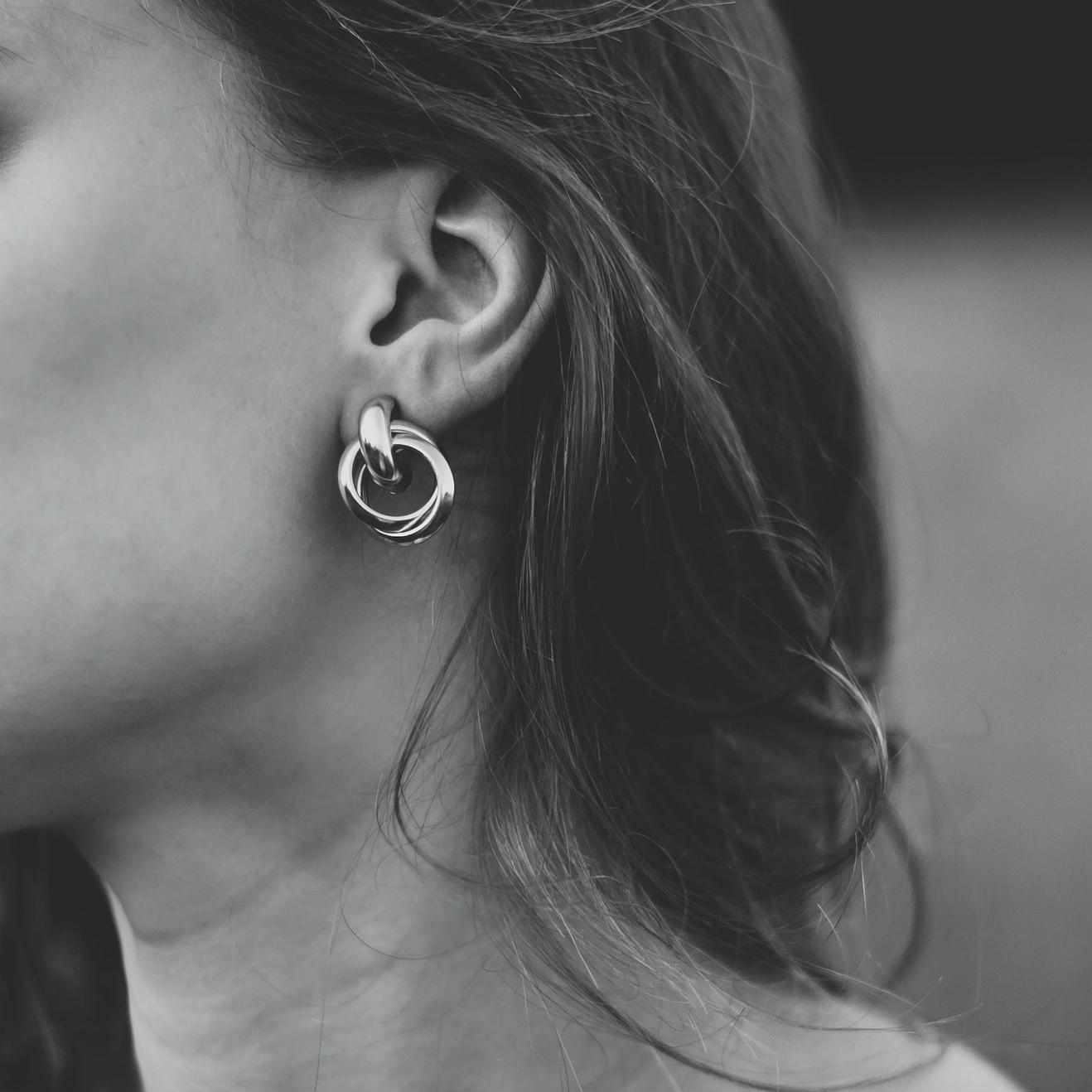 grayscale photo of woman wearing silver stud earring